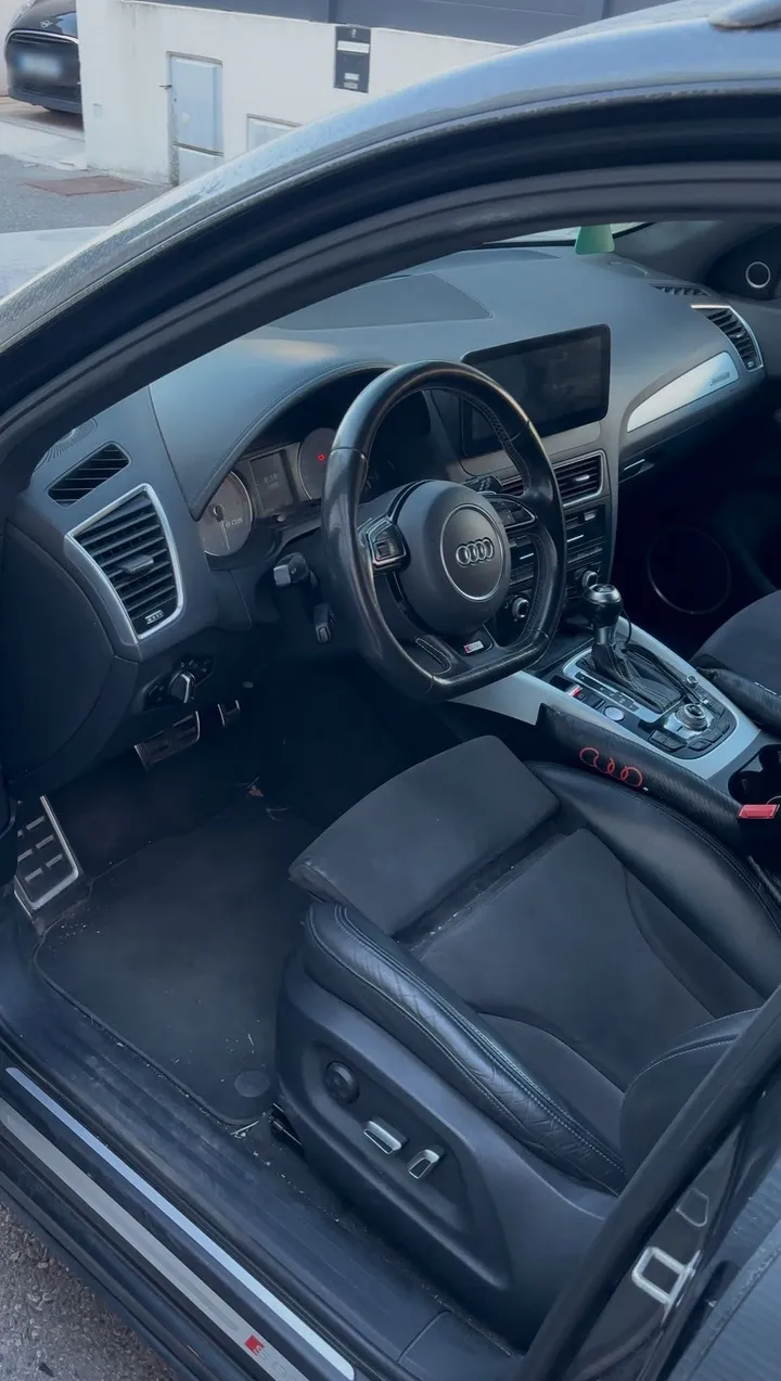 Habitacle d'Audi SQ5 avant nettoyage : poussière sur la console et le tapis